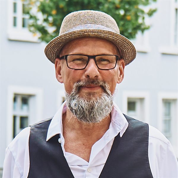 Horst Müller-Fußhöller, Inhaber von HMF-IT, lächelt freundlich vor einer hellen Fassade